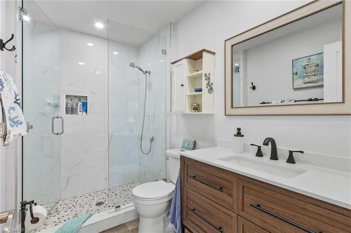 Bathroom featuring solid surface counter, walk in glassed shower and premium lighting.