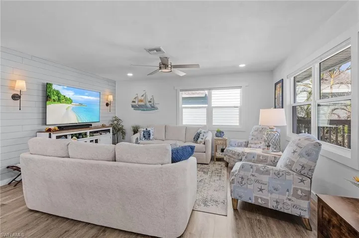 Living room with ceiling fan, beautiful luxury vinyl flooring throughout the entire level.  All new windows that are hurricane rated . . . no shutters to install.