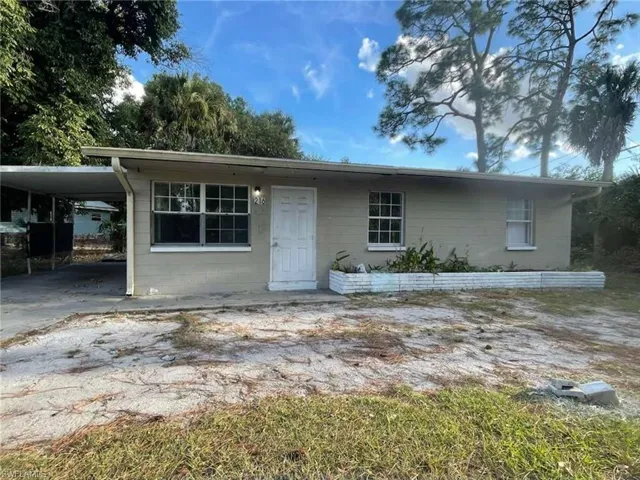 View of front of home featuring a carport, concrete block siding, and driveway