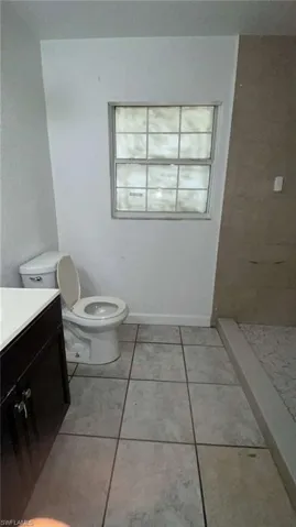 Full bathroom with vanity, light tile patterned floors, and a tile shower