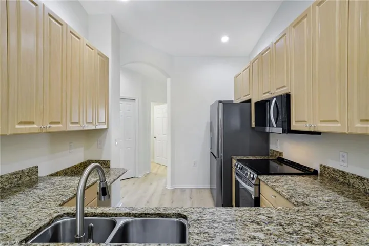 Kitchen featuring light brown cabinets, range with electric cooktop, light stone countertops, light wood-style floors, and recessed lighting