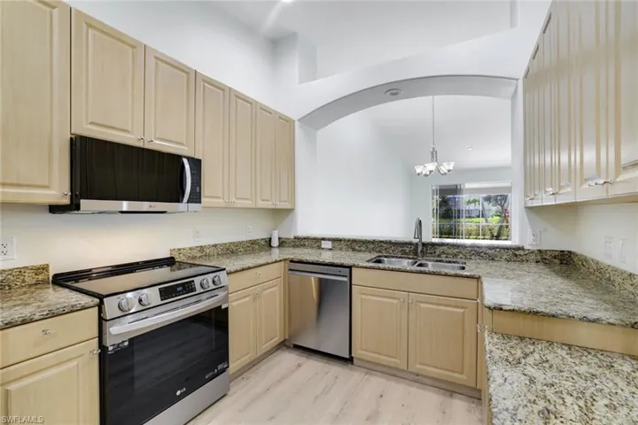 Kitchen featuring appliances with stainless steel finishes, light brown cabinetry, and a chandelier