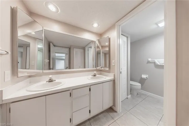 Full bath with a closet, double vanity, light tile patterned floors, and a textured ceiling