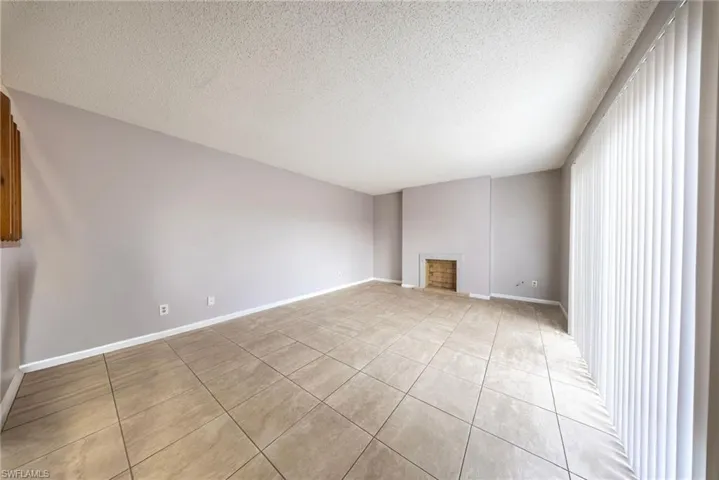 Unfurnished living room with a textured ceiling, light tile patterned floors, and a fireplace