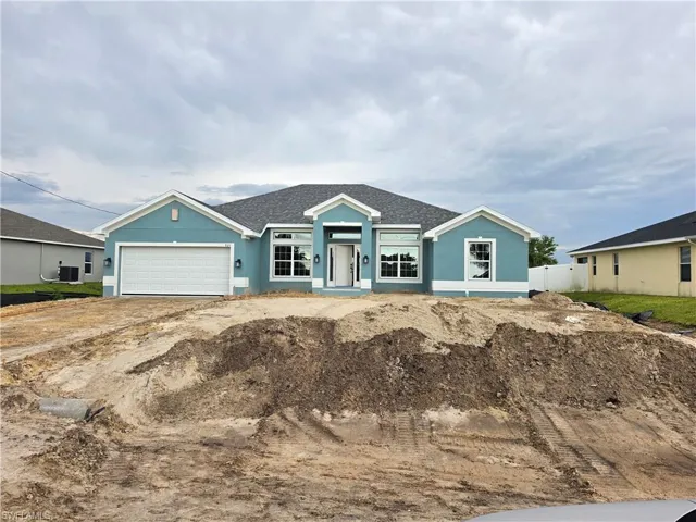 Single-story residence featuring a two-car garage, multiple gables, and a prominent front entrance with sidelights