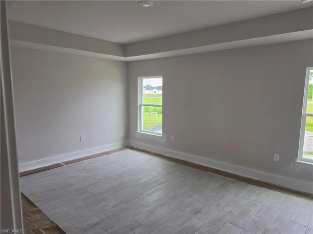 Recessed ceiling with tray detailing, light gray wall paint, and two windows