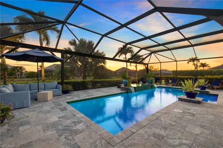 Pool at dusk featuring glass enclosure and a patio area