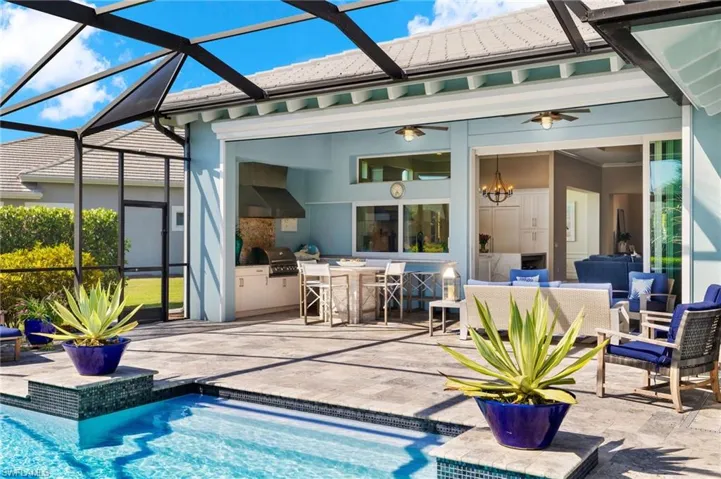 View of swimming pool featuring ceiling fan, a lanai, a patio, and grilling area