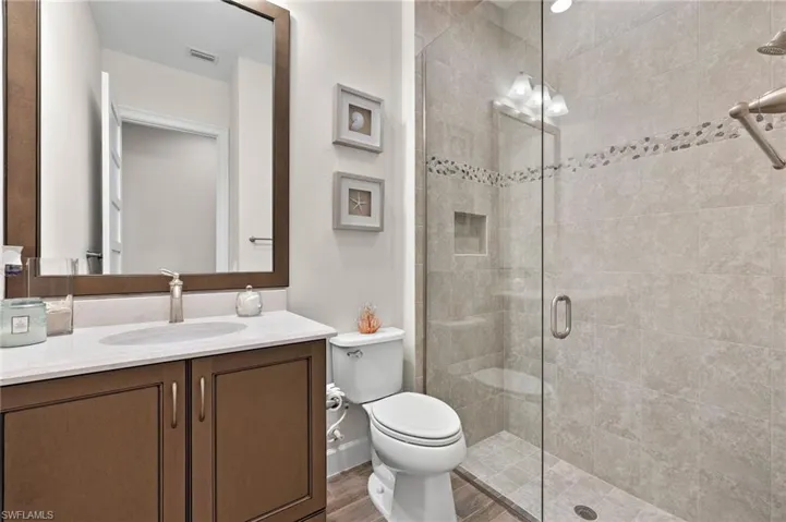 Bathroom with a shower with shower door, hardwood / wood-style flooring, oversized vanity, and toilet