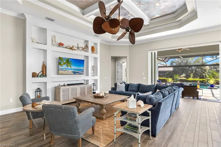 Living room featuring a tray ceiling, crown molding, ceiling fan, and hardwood / wood-style floors