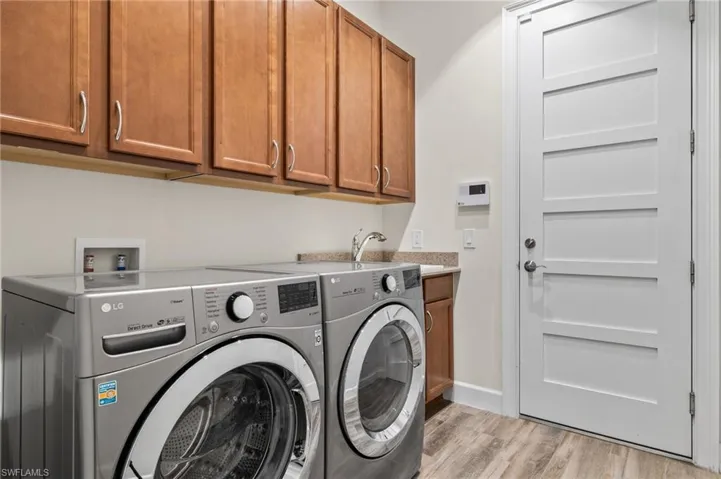 Washroom with cabinets, light hardwood / wood-style floors, hookup for a washing machine, washer and dryer, and sink