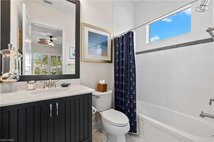 Full bathroom featuring shower / bath combo with shower curtain, ceiling fan, oversized vanity, and toilet