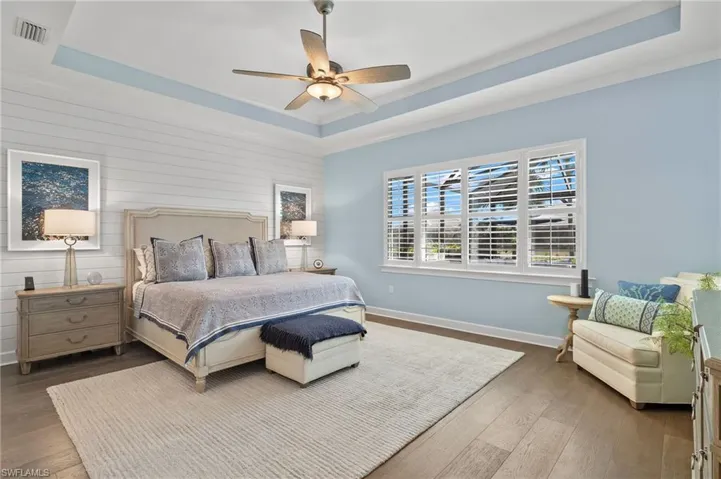 Bedroom featuring ceiling fan, a raised ceiling, and wood-type flooring