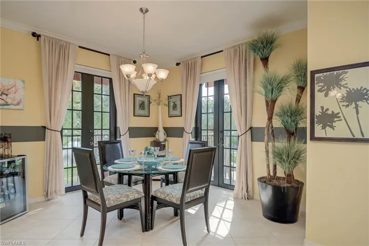 Tiled dining space featuring french doors, a chandelier, wine cooler, and crown molding