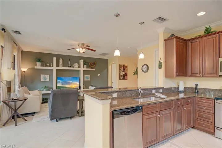 Kitchen with dark stone countertops, stainless steel appliances, ornamental molding, decorative light fixtures,