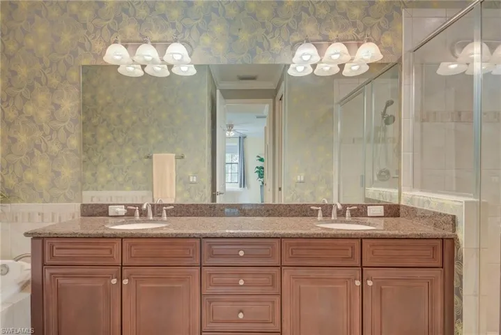 Full bath featuring wallpapered walls, a stall shower, double vanity, and a ceiling fan