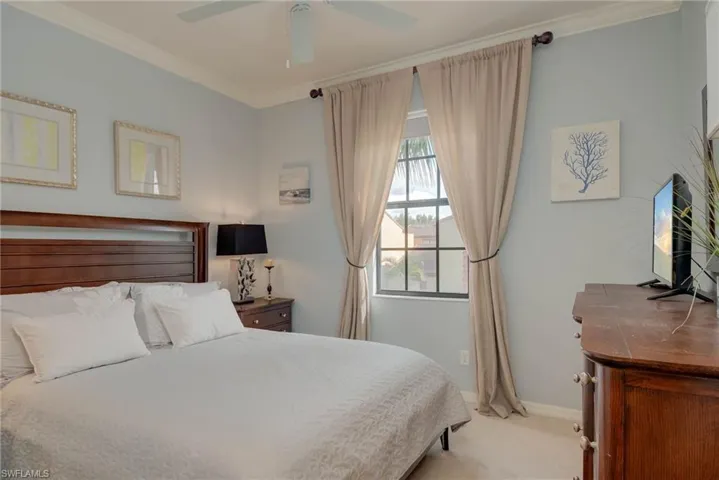 Carpeted bedroom with ornamental molding and a ceiling fan
