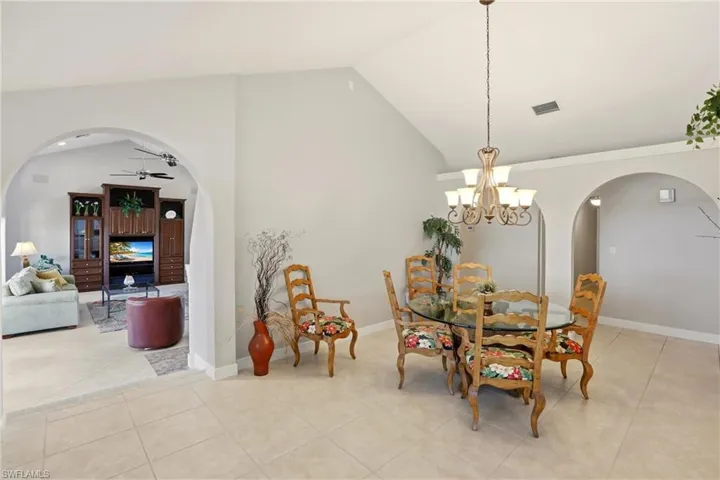 Dining area featuring arched walkways, vaulted ceiling, a ceiling fan, light tile patterned floors, and hanging lights