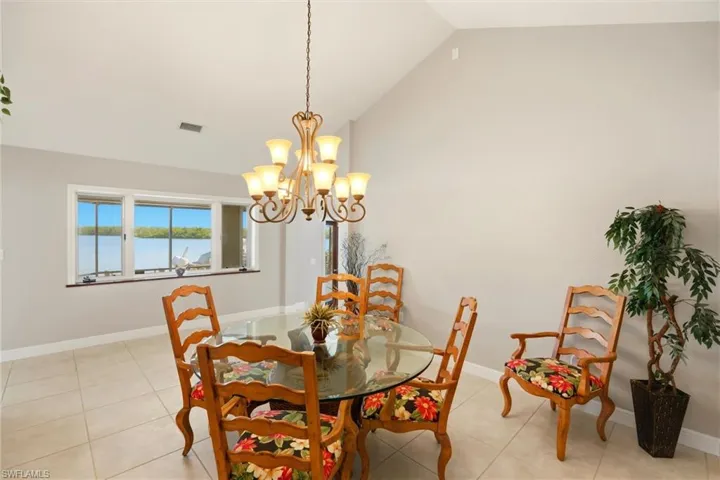 Dining area featuring lofted ceiling, hanging lights, and light tile patterned flooring
