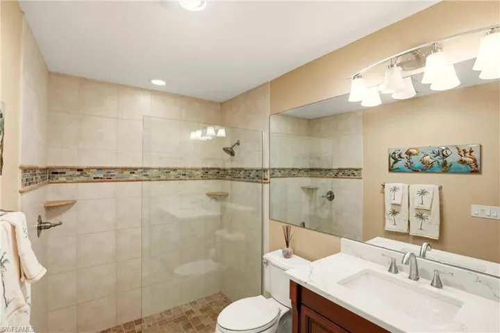 Guest bathroom with tiled shower and vanity with quartz countertop.
