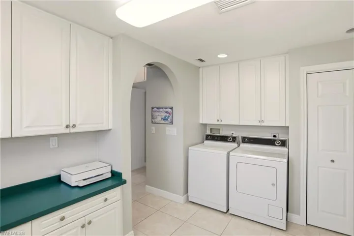 Laundry area featuring cabinet space, arched walkways, washer and dryer.
