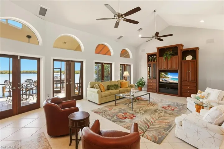 Living room featuring ceiling fans, french doors that span across the back wall and open to the spacious screened lanai.