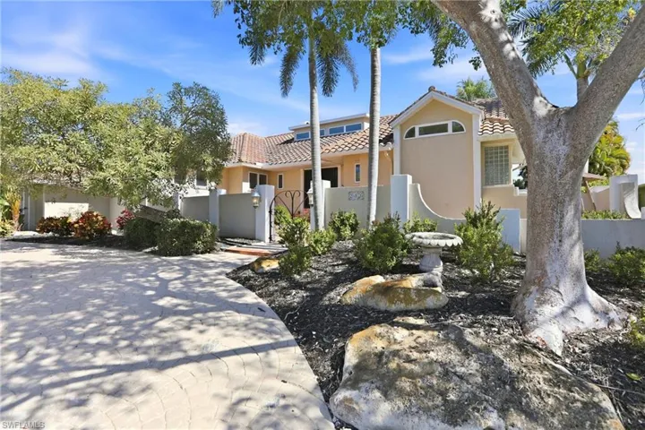 Mediterranean / spanish home with a tiled roof, stucco siding, and a gate