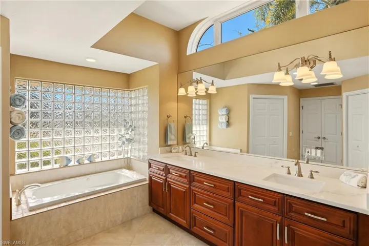 Full bath with double vanity with quartz countertop, a jetted tub,  two walk-in closets,, and a separate shower.