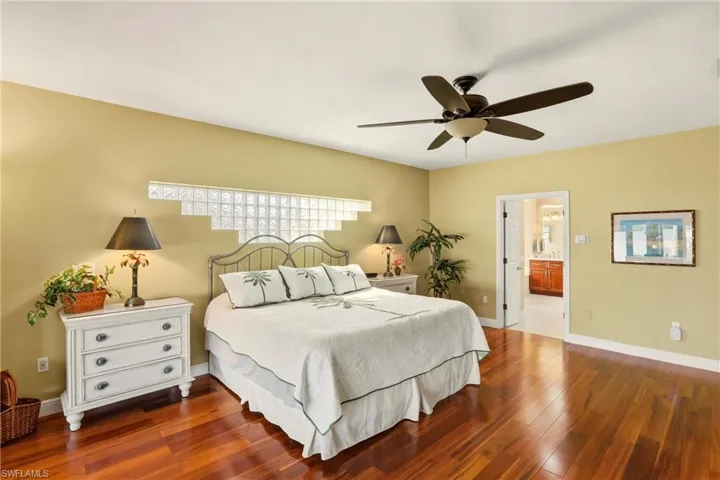 Bedroom featuring dark wood floors, ensuite bath, and ceiling fan