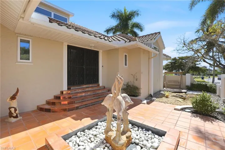 Enclosed entry courtyard with decorative water fountain and serene sitting area with teak swing.
