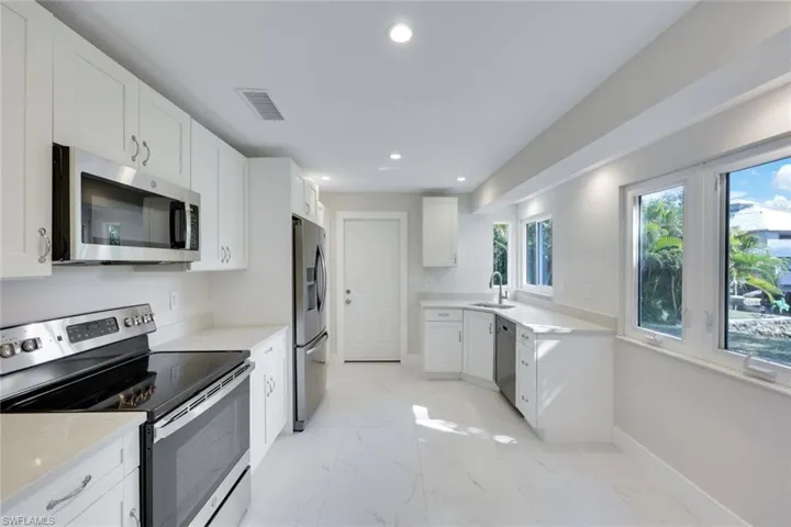 Kitchen features stainless steel appliances, quartz countertops, and shaker cabinets.