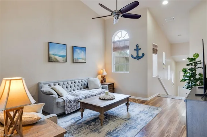 Spacious living area featuring high vaulted ceilings, wood-finish flooring, and an arched window with detailed muntins