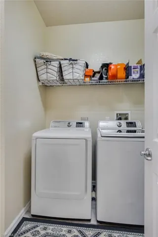 Laundry area featuring a wire shelving unit, light-colored walls, and a patterned floor mat