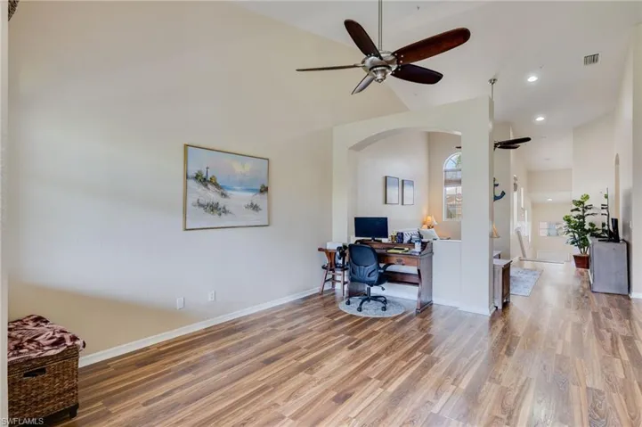 Vaulted ceiling with a ceiling fan, wood-finish flooring, and arched architectural details