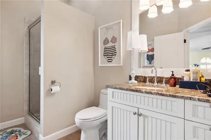 Bathroom with tile patterned floors, walk in shower, vanity, and toilet