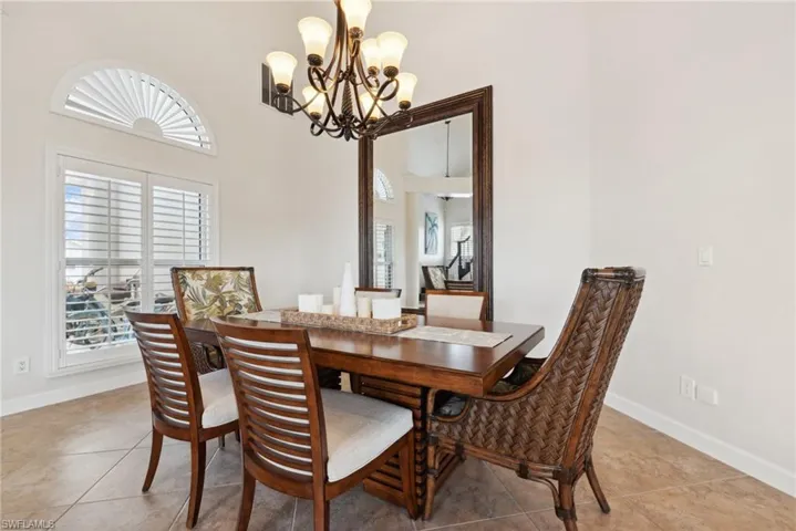 Dining area featuring light tile patterned flooring, a high ceiling, and a chandelier