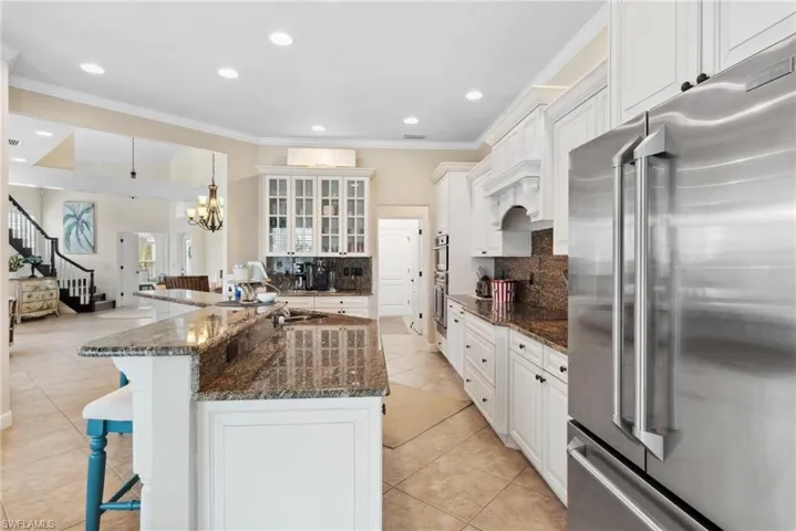 Kitchen featuring white cabinetry, tasteful backsplash, dark stone countertops, a kitchen bar, and high quality fridge