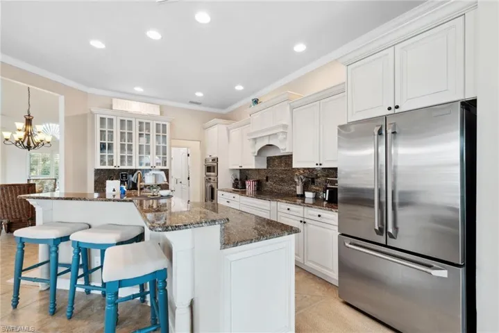 Kitchen with dark stone counters, white cabinetry, a breakfast bar area, and stainless steel appliances