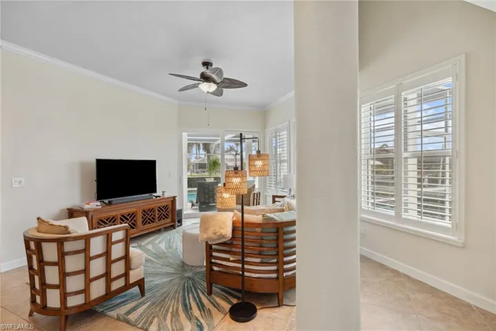 Tiled living room featuring ceiling fan, crown molding, and a healthy amount of sunlight