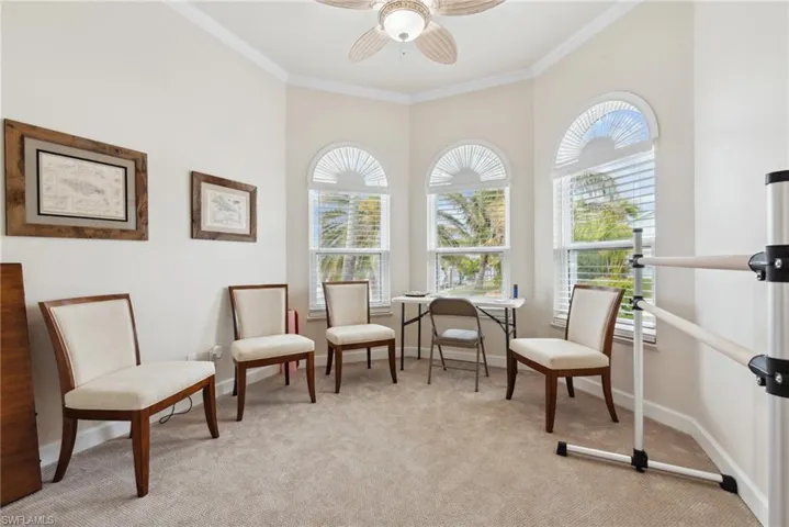 Living area with light carpet, ceiling fan, and ornamental molding