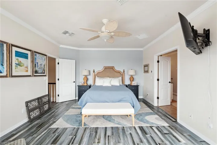 Bedroom featuring ceiling fan, ornamental molding, and dark wood-type flooring