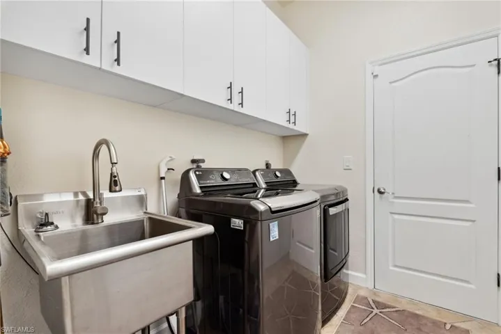 Laundry area featuring cabinets, separate washer and dryer, sink, and light tile patterned floors