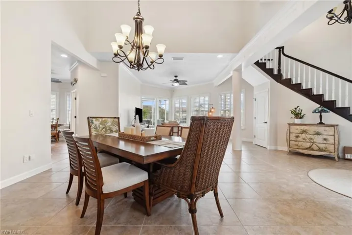 Tiled dining space featuring ceiling fan with notable chandelier and ornamental molding