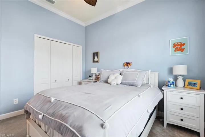 Carpeted bedroom featuring ceiling fan, a closet, and crown molding