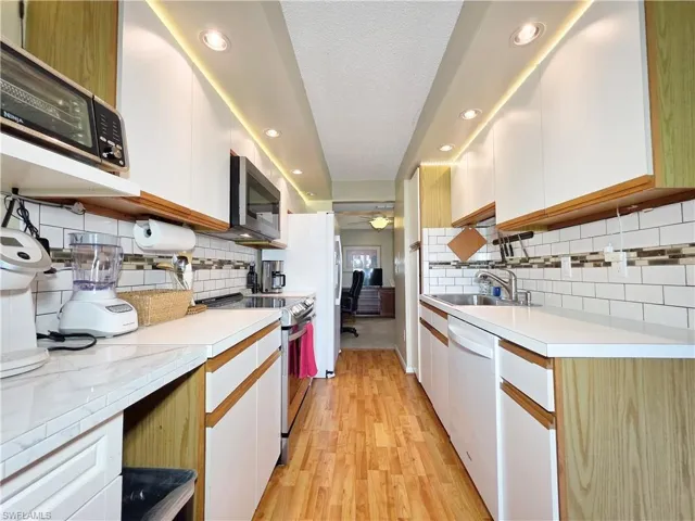 Kitchen featuring appliances with stainless steel finishes, a ceiling fan, light countertops, recessed lighting, and brown cabinets