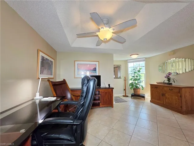 Office space with light tile patterned floors, ceiling fan, and a textured ceiling