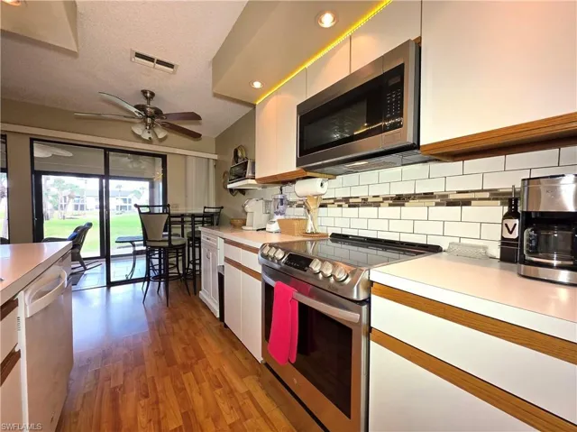 Kitchen featuring appliances with stainless steel finishes, white cabinets, light countertops, a textured ceiling, and light wood-type flooring