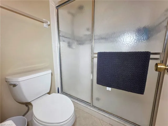 Full bathroom featuring a shower stall and light tile patterned flooring