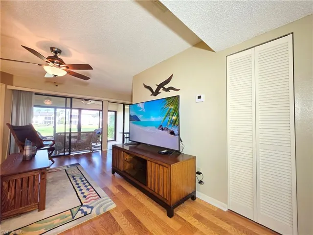 Living area with a textured ceiling, wood finished floors, and a ceiling fan