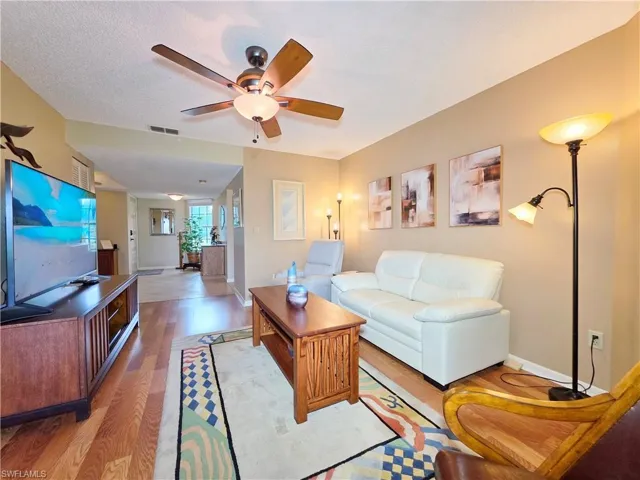 Living room with a ceiling fan, light wood-style floors, and a textured ceiling